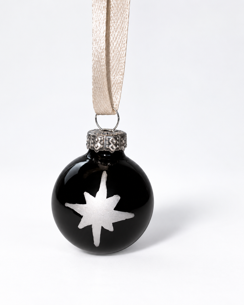 Handmade glossy black glass Christmas ornament with white silver polar star design and cream ribbon hanger