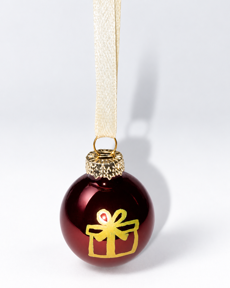 Handmade glossy dark brown glass Christmas ornament with gold gift box design and cream ribbon hanger