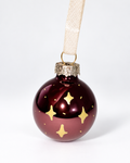 Handmade glossy dark brown glass Christmas ornament with gold four-pointed star design and cream ribbon hanger