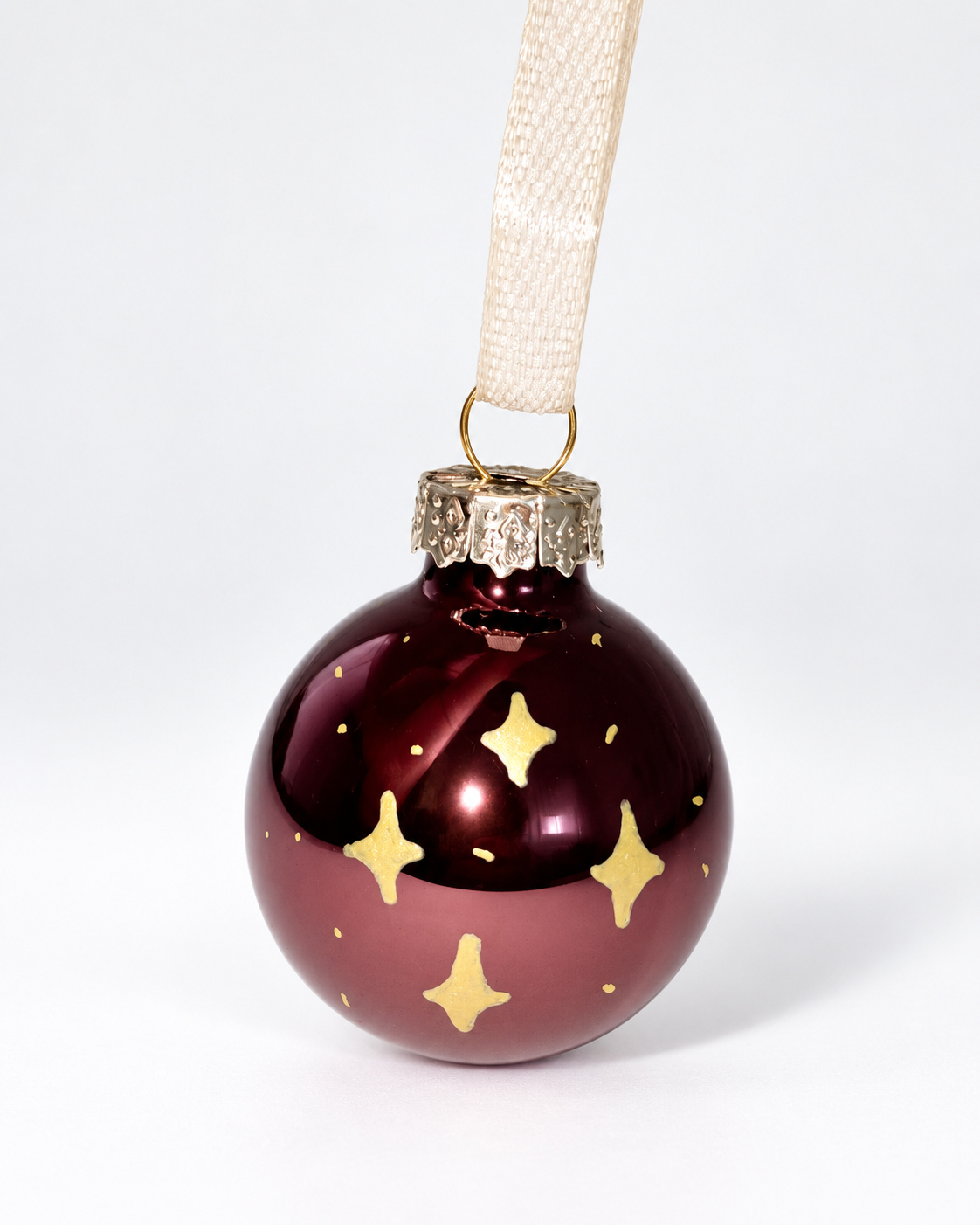 Handmade glossy dark brown glass Christmas ornament with gold four-pointed star design and cream ribbon hanger
