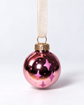 Handmade glossy pink glass Christmas ornament with pink four-pointed star design and cream ribbon hanger