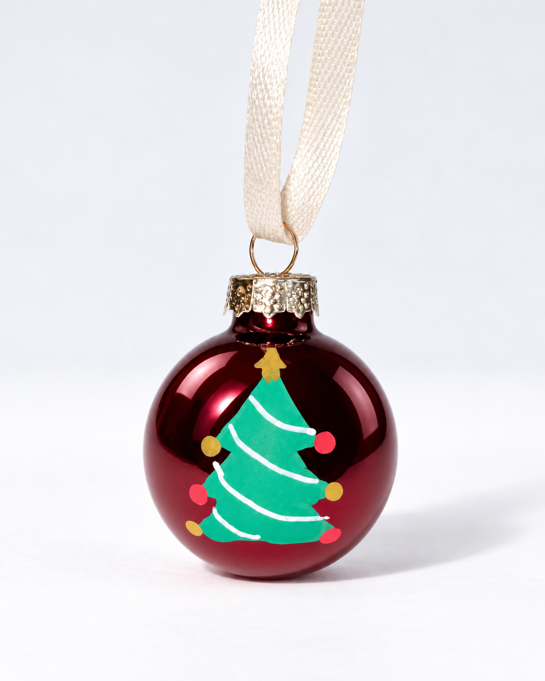 Handmade glossy dark red glass Christmas ornament with colourful painted Christmas tree and white ribbon hanger