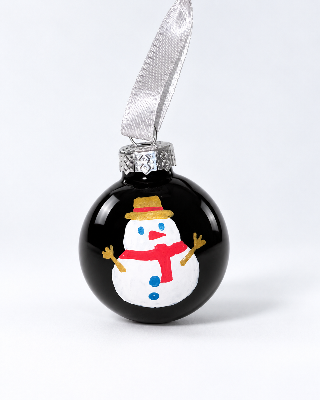 Handmade shiny black glass Christmas ornament with painted snowman in golden hat and red scarf, silver ribbon hanger