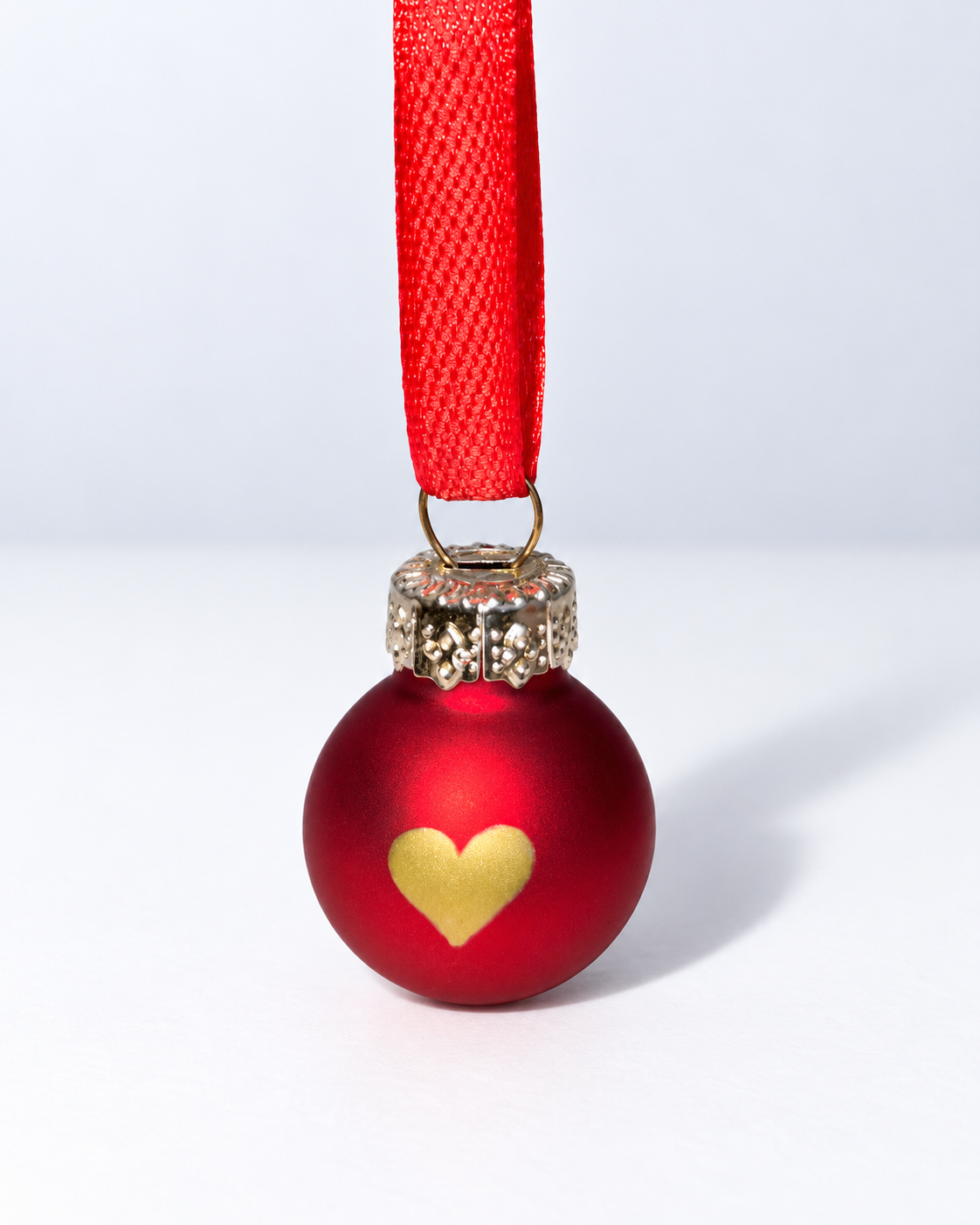 Tiny handmade matte red glass Christmas ornament with gold heart design and red ribbon hanger