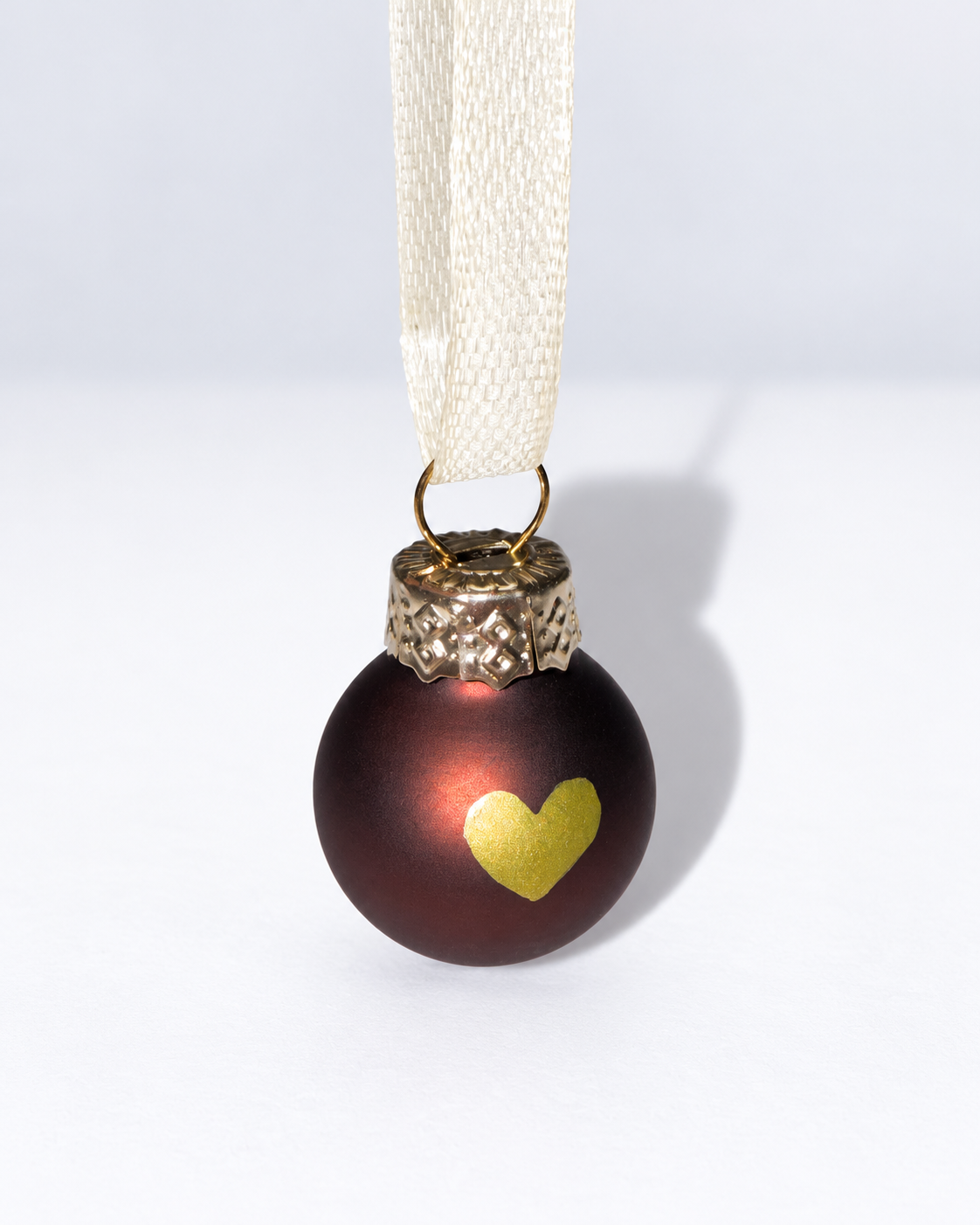 Tiny handmade dark brown glass Christmas ornament with gold heart design and white ribbon hanger