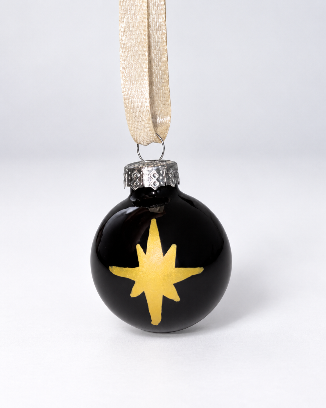 Handmade shiny black glass Christmas ornament with gold polar star design and gold ribbon hanger