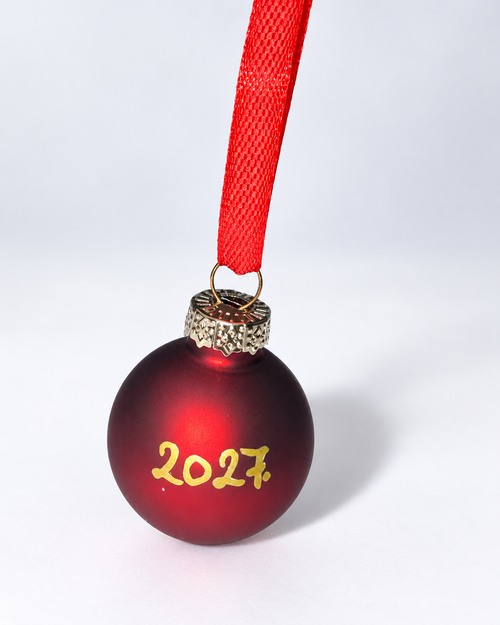 Handmade dark red glass Christmas ornament with gold 2027 lettering and red ribbon hanger